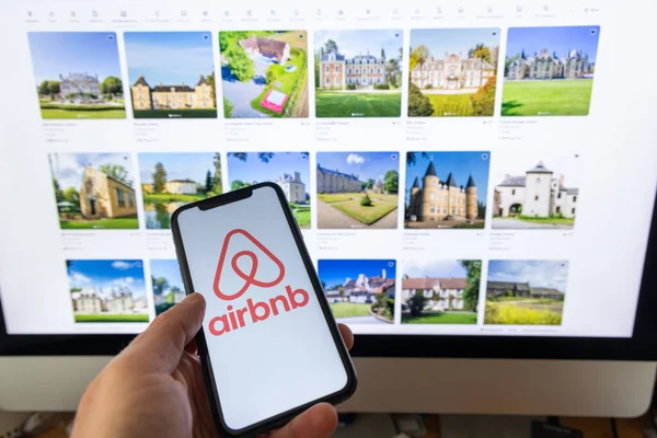 フランス 2023年11月30日 Airbnbアプリケーションを搭載したスマートフォンを持ち歩く女性手 Airbnbはオンラインマーケットプレイスとホスピタリティサービスであり 人々が短期滞在を賃貸または賃貸することを可能にします ストックフォト