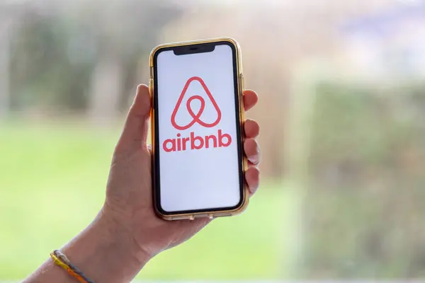フランス 2023年11月30日 Airbnbアプリケーションを搭載したスマートフォンを持ち歩く女性手 Airbnbはオンラインマーケットプレイスとホスピタリティサービスであり 人々が短期滞在を賃貸または賃貸することを可能にします ストック写真