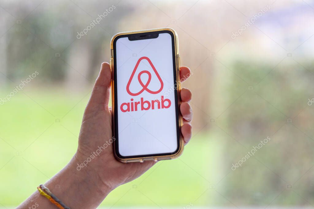 Paris,  France - November 30, 2023 : Female hand holding smartphone with Airbnb application. Airbnb is an online marketplace and hospitality service, enabling people to lease or rent short-term lodging