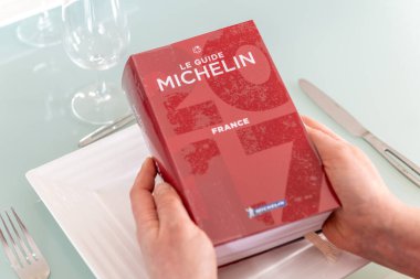 Paris, Fransa - 15 Şubat 2021 - Restoranları eleştiren Red Michelin rehber kitabı okuyan kadın.