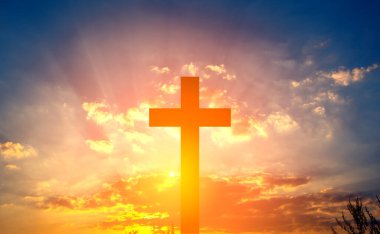 Cross in the rays of the sun against a blue cloudy sky.  Banner for text about religion.