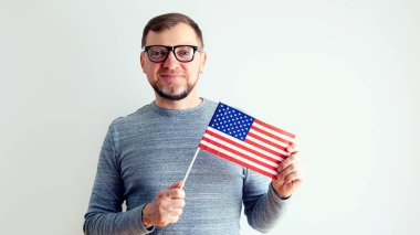 Amerikan bayrağı taşıyan adam. Gri arka planda gözlüklü orta yaşlı bir adam..
