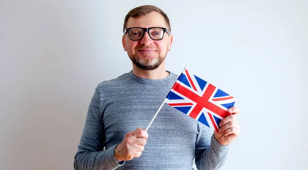 Man with UK flag. Middle aged man with glasses on a gray background.