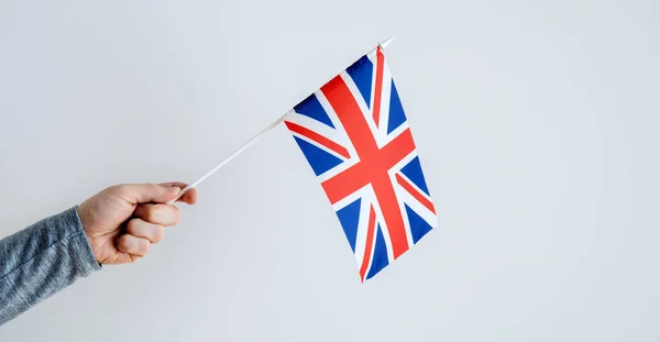 Close-up, man\'s hand holding the UK flag. Place for text about learning English.
