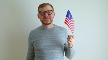 Amerikan bayrağı taşıyan gözlüklü orta yaşlı bir adam. Elindeki bayrağı gösteriyor. Amerika Birleşik Devletleri 'ne göç.