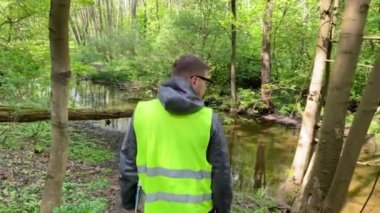Erkek ekolojist, çevre orman nehrinin durumunu kaydediyor. Çevre denetimi.