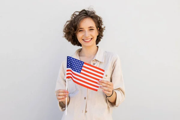 Młoda Uśmiechnięta Szczęśliwa Kobieta Trzymać Amerykańską Flagę Wygląd Kamery Szarym — Zdjęcie stockowe