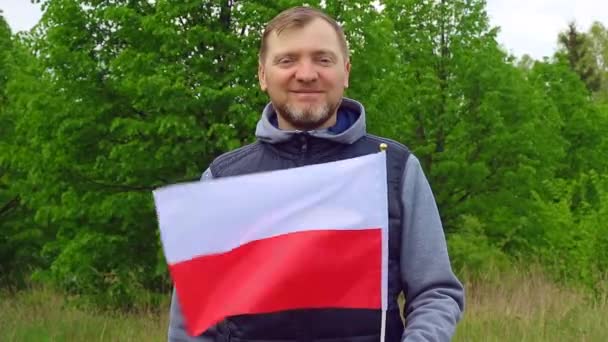 ポーランドの自然を背景にポーランドの国旗を掲げる中年男性 — ストック動画