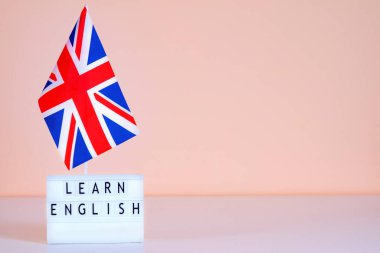 İngiliz bayrağı ve metni, İngilizceyi pembe bir duvarda öğreniyor. İngilizce kursları hakkında sunum için model.
