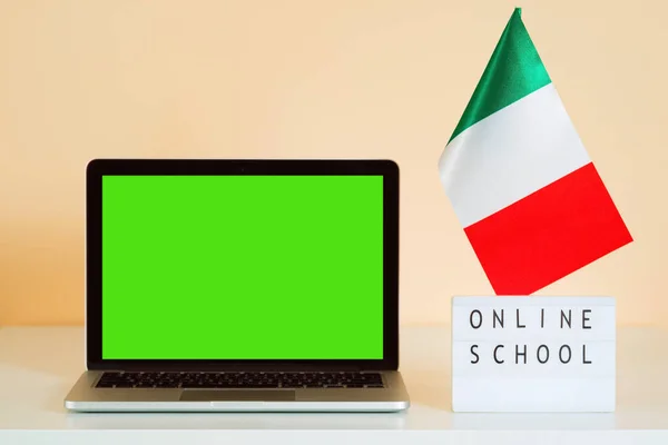 Laptop with green screen and Italy flag and display with text ONLINE SCHOOL. Italian language course.