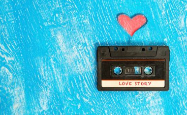 Kalp şeklinde bant ve mavi ahşap arka planda aşk hikayesi içeren Retro ses kaseti.