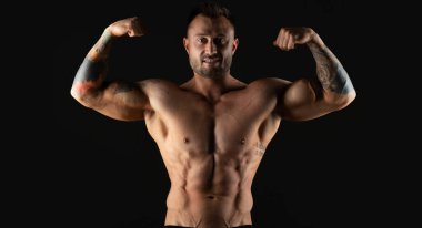 Vücut geliştirici, güçlü atletik adam. Fitness modeli, kaslı ve karın kaslı. Kopyalama alanı olan siyah bir arkaplanda izole edilmiş.