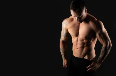 Vücut geliştirici, güçlü atletik adam. Fitness modeli, kaslı ve karın kaslı. Kopyalama alanı olan siyah bir arkaplanda izole edilmiş.
