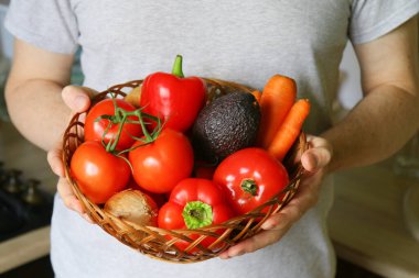 Erkek eli yakından, elinde domates, kırmızı biber, avokado ve havuç tutan adam. Beslenme sebze salatası hazırlamak için gerekli malzemeler.