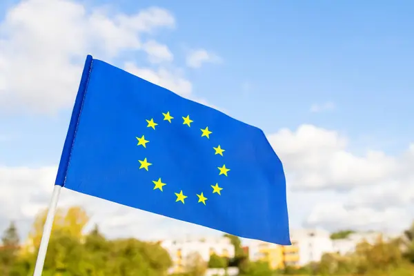 Vifta Europeiska Unionens Flagga Mot Bakgrund Staden Och Den Blå Stockbild