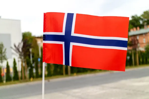Lambaikan Bendera Norwegia Terhadap Latar Belakang Sebuah Jalan Kota Stok Gambar