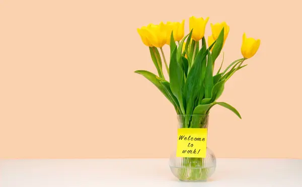 花瓶里有一束黄色的郁金香和题词欢迎大家来工作 案文的位置 图库图片