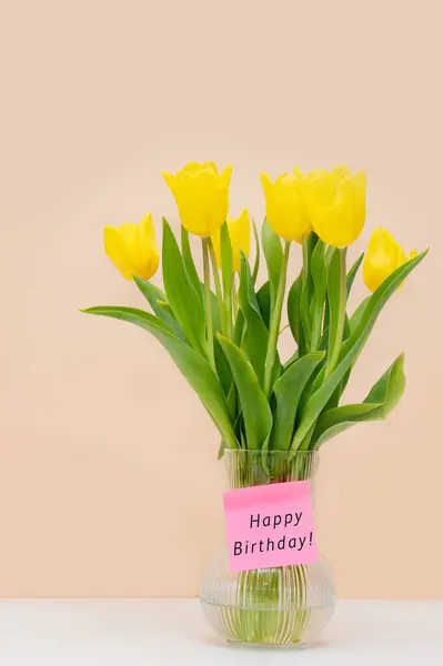 花瓶里的一束美丽的黄色郁金香花和题词 生日快乐 带有文字空间的垂直照片 免版税图库图片