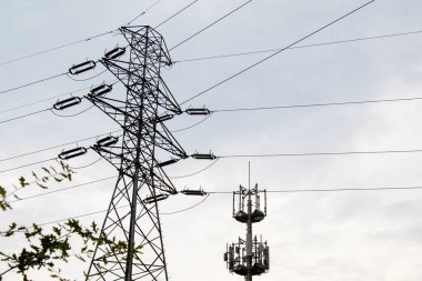 High voltage power line pole and a tower with antennas for mobile communications and the Internet.	