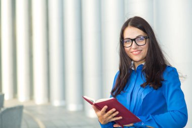 İş kadını 30 yaşında, gözlüklü. Ofis girişinde mavi gömlekli genç bir kadın var..