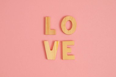 Aşk kelimesi pembe arka plandaki ahşap harflerden yapılmıştır..