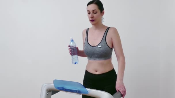 Ung Kvinna Tränar Löpband Och Dricksvatten För Att Återfukta Kroppen — Stockvideo