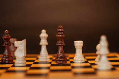 Koyu arkaplanda tahta üzerinde satranç taşları