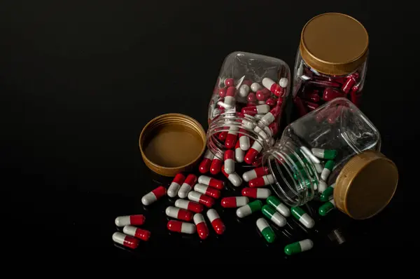 İlaç şişesinin içindeki, şişenin dışına ve yanına saçılmış bir şırınga. Kullanımı ve dozajına uygun değilse ilaç kullanmanın tehlikelerini gösteren koyu bir arka planı var.