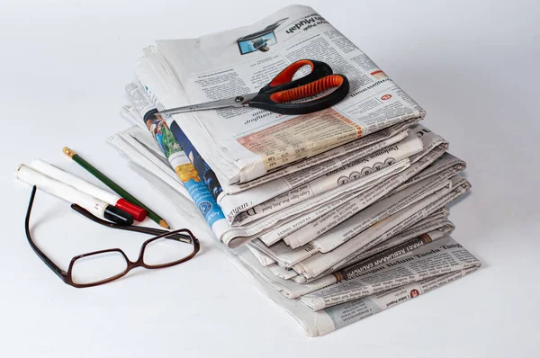İş ve finans haberleri için okunması gereken bir yığın gazetenin yanı sıra masaya konmuş kırtasiye ve bardaklar, hafif bir arkaplan kullanarak fotoğraf çekiliyor.