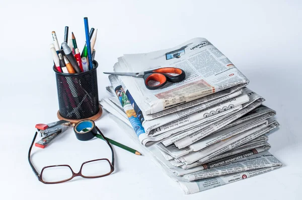 İş ve finans haberleri için okunması gereken bir yığın gazetenin yanı sıra masaya konmuş kırtasiye ve bardaklar, hafif bir arkaplan kullanarak fotoğraf çekiliyor.