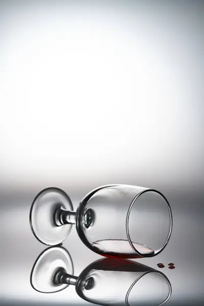 Arka planda kırmızı bir şarap bardağı ve cam duruşu.