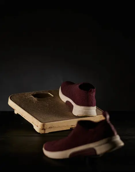 Uzun zamandır giyilmeyen terazilerdeki ayakkabılar tozdan görülebiliyor ve koyu bir arkaplanda fotoğraflanmış diğer pislikler.