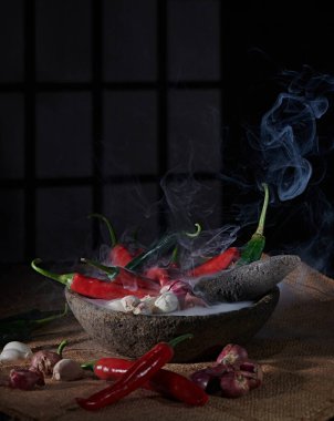 Büyük kırmızı ve yeşil biberler, hafif bir dumanla karakterize edilmiş baharatlı acı biber sosu yapmak için arpacık soğanı ve sarımsakla karıştırılmaya hazır..