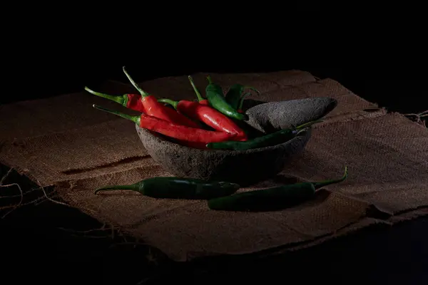 Büyük kırmızı ve yeşil biberler, hafif bir dumanla karakterize edilmiş baharatlı acı biber sosu yapmak için arpacık soğanı ve sarımsakla karıştırılmaya hazır..