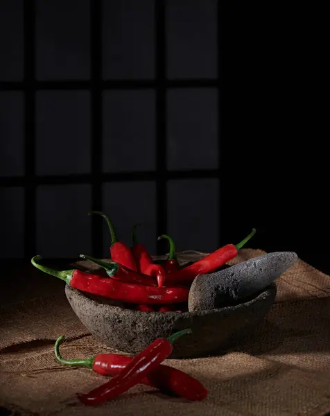 Büyük kırmızı biberler, hafif dumanla karakterize edilmiş baharatlı bir biber sosu yapmak için taş havan ve tokmakla dövülmeye hazırdır..