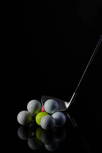Golf sopası ve golf topu karanlık bir arkaplanda fotoğraflanmış ve fotoğrafta yansımalar var.