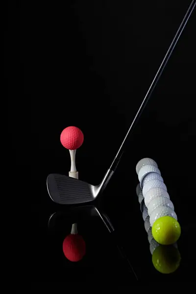 Golf sopası ve golf topu karanlık bir arkaplanda fotoğraflanmış ve fotoğrafta yansımalar var.