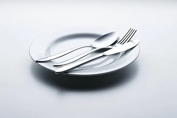 Beyaz arka planda kaşıklar, çatallar, bıçaklar, fincanlar ve plakalar gibi gümüş renkli çatal bıçaklar fotoğraflandı