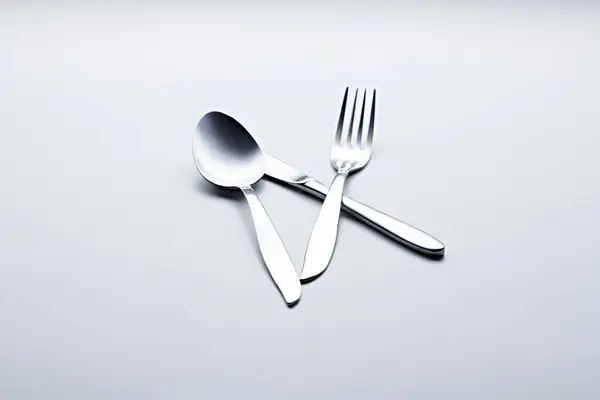 Beyaz arka planda kaşıklar, çatallar, bıçaklar, fincanlar ve plakalar gibi gümüş renkli çatal bıçaklar fotoğraflandı