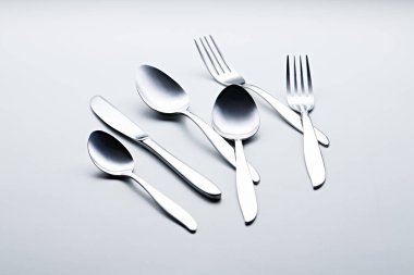 Beyaz arka planda kaşıklar, çatallar, bıçaklar, fincanlar ve plakalar gibi gümüş renkli çatal bıçaklar fotoğraflandı