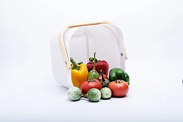 Plastik bir kesim tahtasına yerleştirilmiş taze sebzeler ve meyveler beyaz arka planda fotoğraflanmış.