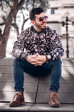Young man with dark glasses sitting smiling