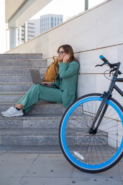 Kadını Ofis Binasının Merdivenlerinde Oturmuş Bilgisayarla Bisikletin Yanında Çalışıyor — Stok fotoğraf