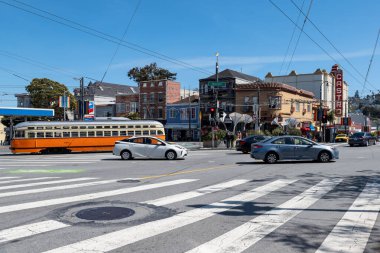 Castro Bölgesi, San Francisco, Kaliforniya, ABD - 23 Nisan 2023: Bulutsuz mavi gökyüzüne karşı Castro tiyatrosu yakınlarında beyaz lekeli asfalt yolda araçları taşımak
