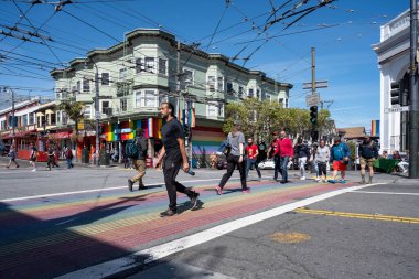 Haight Ashbury Caddesi, San Francisco, Kaliforniya, ABD - 23 Nisan 2023: Güneşli ve bulutsuz mavi gökyüzünde şehir binalarına karşı renkli kaldırımlarda yürüyen yayalar ile dolu cadde