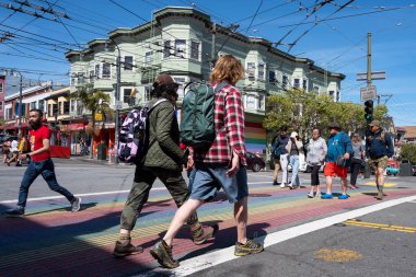 Haight Ashbury Caddesi, San Francisco, Kaliforniya, ABD - 23 Nisan 2023: Güneşli ve bulutsuz mavi gökyüzünde şehir binalarına karşı renkli kaldırımlarda yürüyen yayalar ile dolu cadde