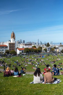 San Francisco, California - 25 Nisan 2023: İnsanlar mavi gökyüzüne karşı ilkbahar boyunca Dolores Park Misyonunda boş vakitlerin tadını çıkarıyorlar