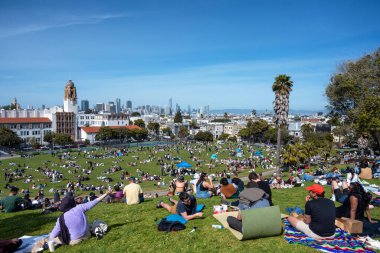 San Francisco, California - 25 Nisan 2023: İnsanlar mavi gökyüzüne karşı ilkbahar boyunca Dolores Park Misyonunda boş vakitlerin tadını çıkarıyorlar
