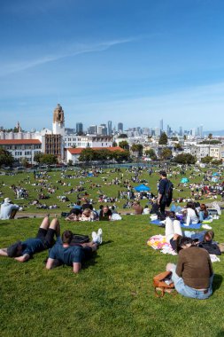 San Francisco, California - 25 Nisan 2023: İnsanlar mavi gökyüzüne karşı ilkbahar boyunca Dolores Park Misyonunda boş vakitlerin tadını çıkarıyorlar