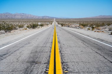 Mojave Çölü boyunca, asfaltta çatlaklar olan boş bir otoyol.